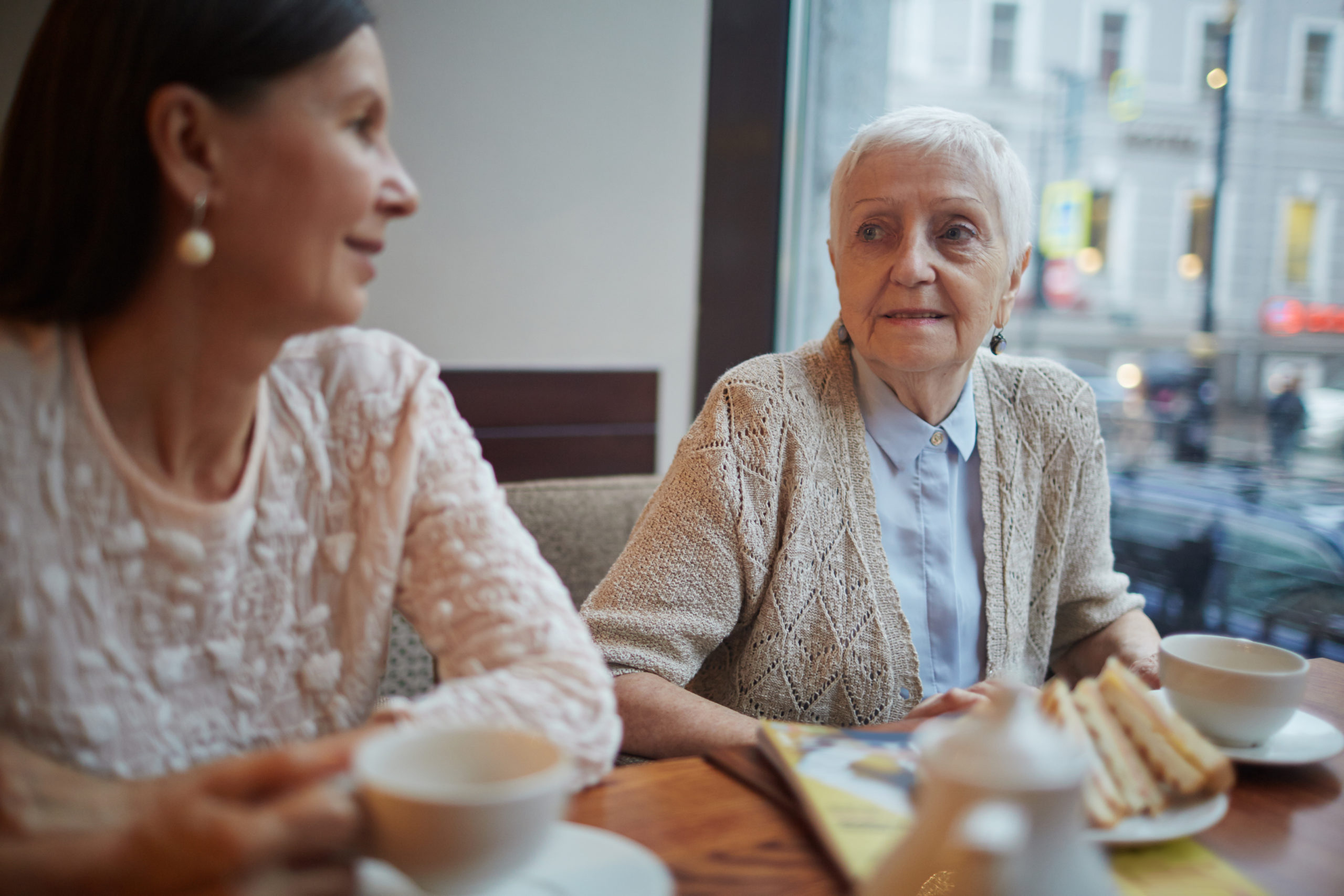 Older person sitting at a table, smiling warmly.