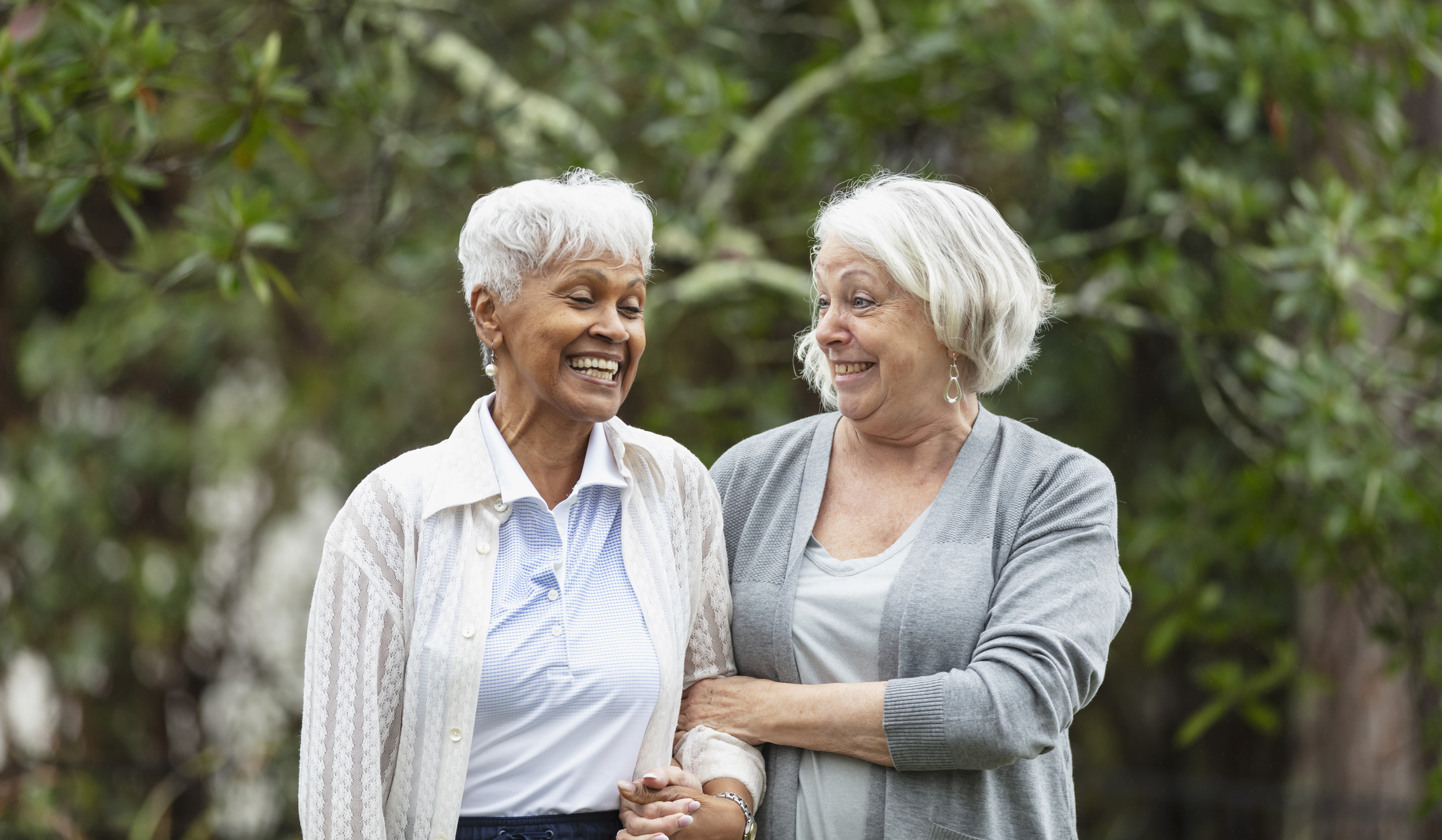 Two elderly women smiling and chatting together, enjoying each other’s company.